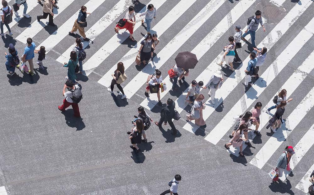 Aerial view of pedestrians crossing a zebra crossing, showing diverse people moving in different directions